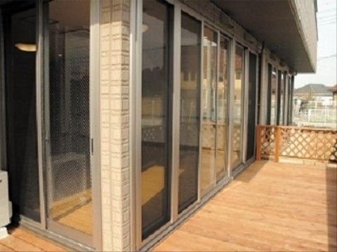 施設から直接出られるＬ字型のウッドデッキがあり、木製の柵が付いている。施設の周囲は一般の住宅が建っている。