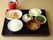 ある日の一食である。黒いプレートに、主食、汁物、主菜、デザートなどが並べられている。栄養バランスが考慮された食事である。