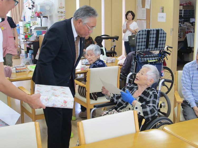 メガネをかけた男性にプレゼントなどを渡されうれしそうな入居者。