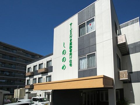 モノトーンの外壁に、緑色で施設名が表示されている施設の外観