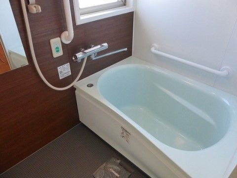 清潔感のある、壁に手すりが設置された陽射しが差し込む浴室
