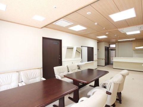 四角形の照明が複数設置され、明るい雰囲気のスペースである。木製のテーブルに白色の１人掛けソファがいくつか用意されている。
