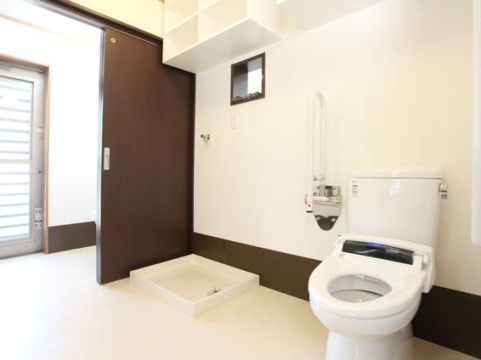 引き戸式の茶色の扉が備え付けられている。出入口が広々としており、車椅子をご利用の方も快適にトイレが使用できる。