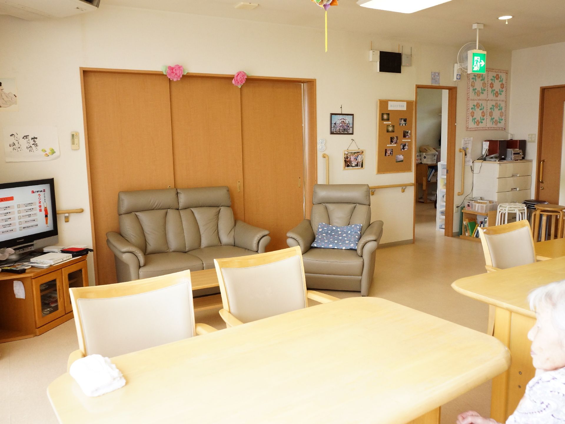 リビングの壁に入居者の手作りの品や写真が飾られている。ソファとテレビがあるのでリラックスして過ごせる。