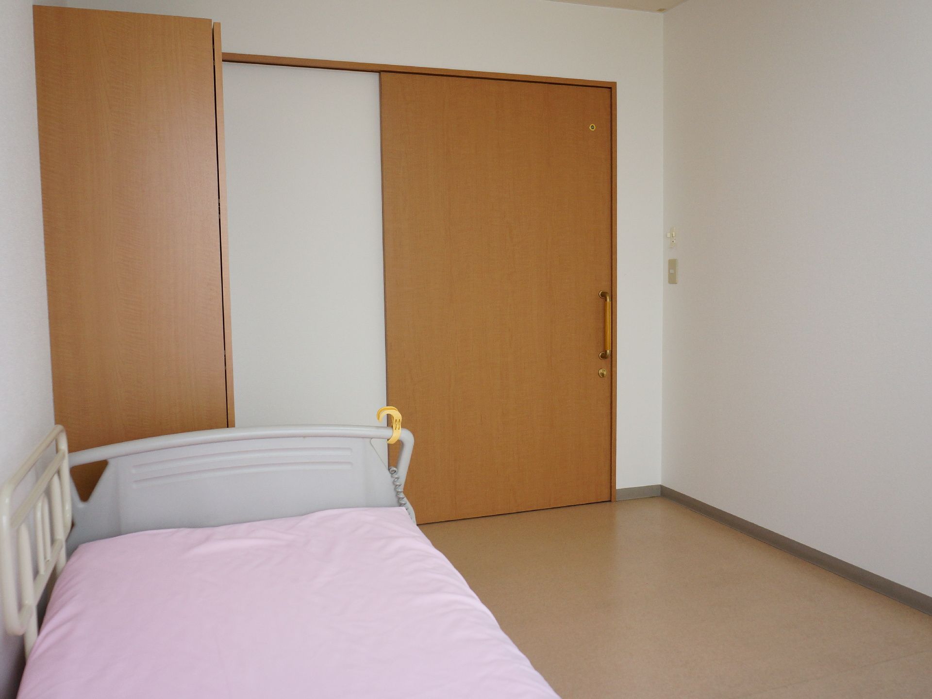 居室のドアは引き戸式になっている。ドアの近くにはベッドが設置されている。また、ベッドには転落を防止するための柵が設置している。
