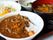 施設で提供される、食事の一例である。ひき肉入りのカレーがメインで、スープとサラダが一緒に提供されている。