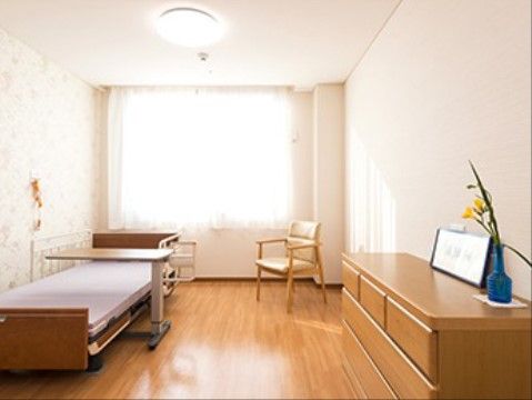 壁にナースコールが設置され、テーブル付きのベッドがある居室