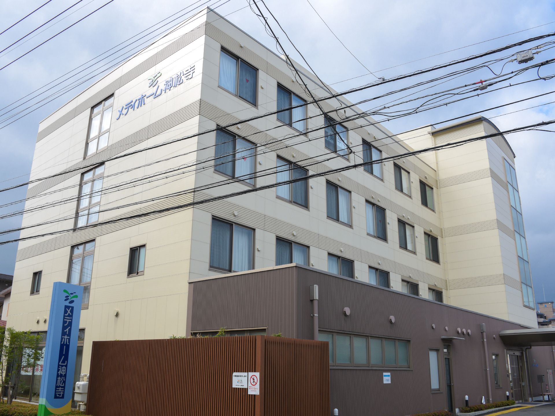 施設は4階建ての建物で、道路から見える外壁の高い位置に大きく施設名が書かれている。また、道にも看板が立てられている。