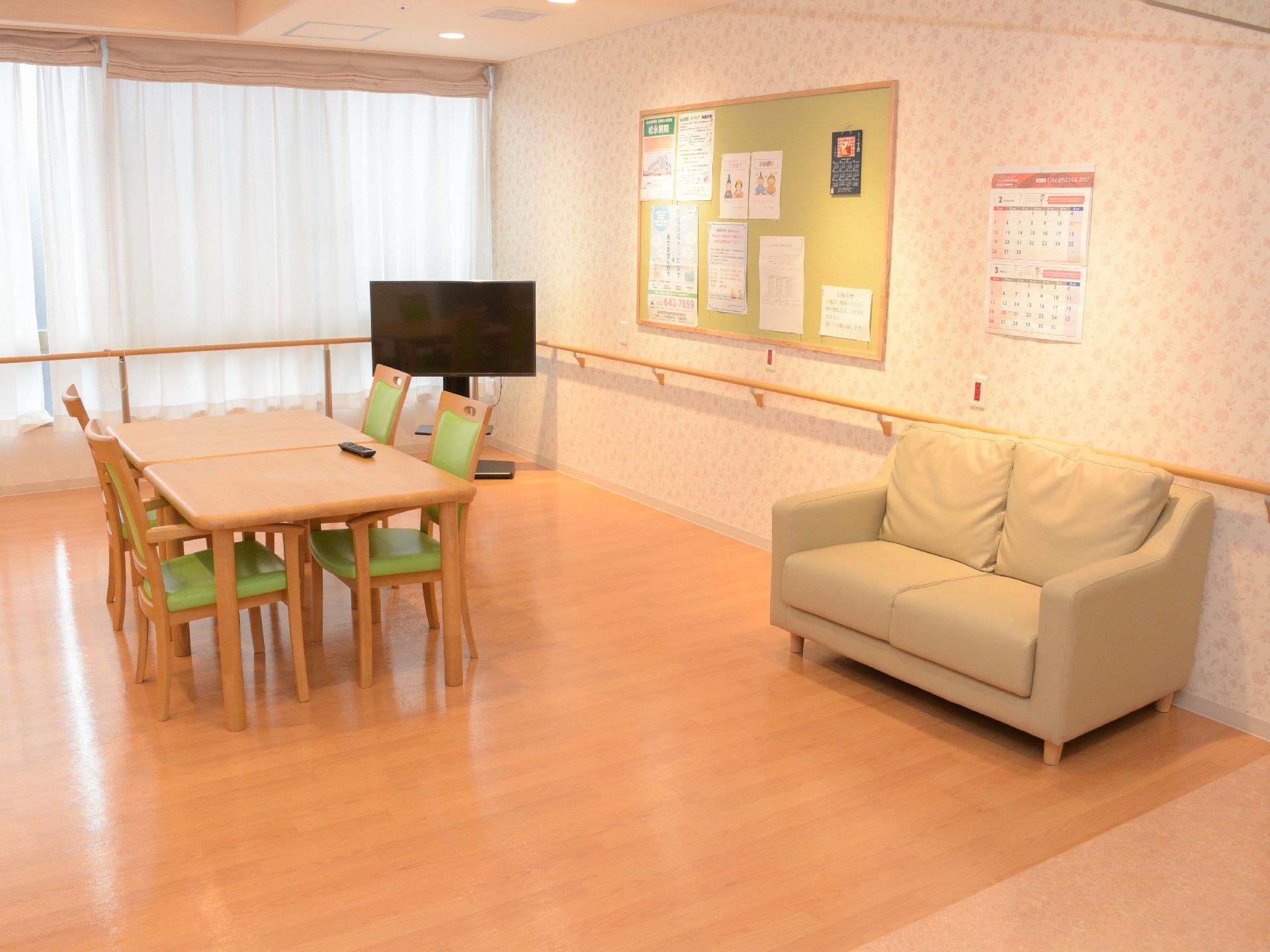 広々とした食堂の壁沿いにはぐるりと手摺りが設置されている。部屋の角にはテレビが置かれ、横には掲示板がある。