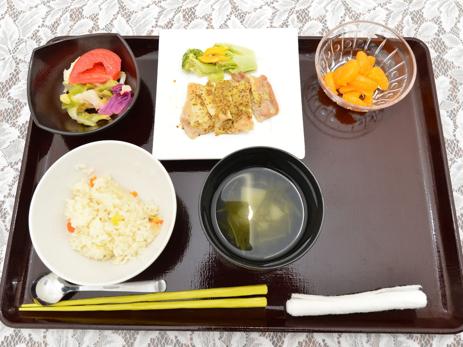 ある日の食事内容の一例。ごはん、汁物、サラダ、メインのおかず、デザートがある。おしぼりもついてくる。
