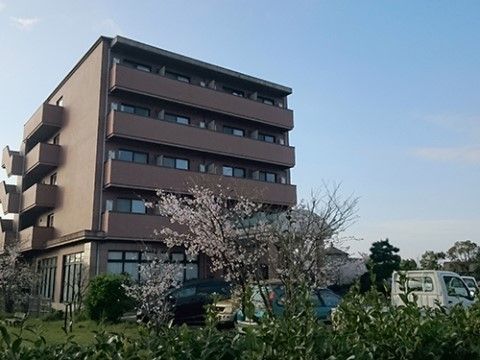 周辺に木々が植えられている、ブラウン色の外壁が特徴の施設外観