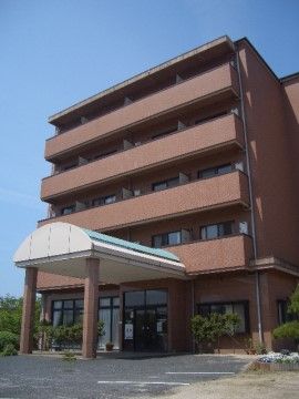落ち着いたブラウンがおしゃれな建物。玄関前には緑の屋根が取り付けられており、雨の日の出入りも安心して行える。