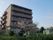 桜の木や植木など自然に囲まれた施設は、落ち着いたブラウンの壁で、マンションのようなシンプルな外観をしている。