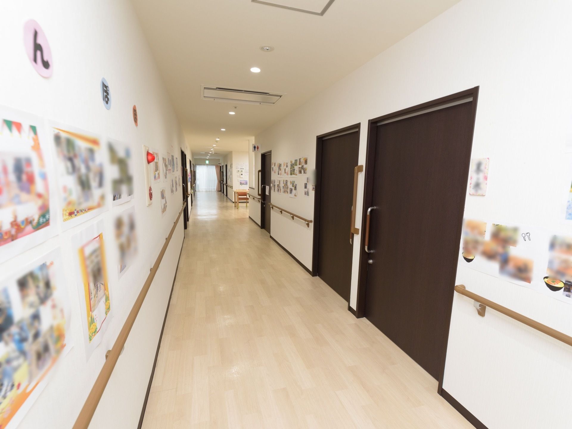 ゆとりある幅のまっすぐな通路があり、左右の壁には、多数の引き戸の扉が並んでいる。扉の間には各種の手すりも設置されている。
