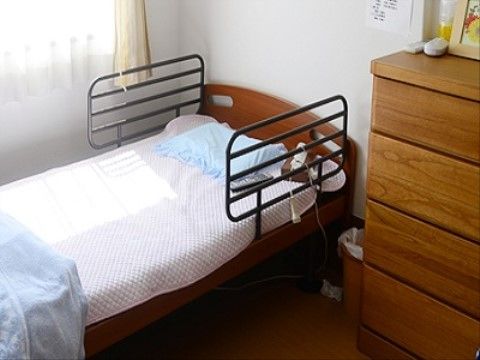 ベッドとタンスの間にはゴミ箱があり、ビニール袋がかけてある。タンスの上には、小さな額などの小物が飾ってある。