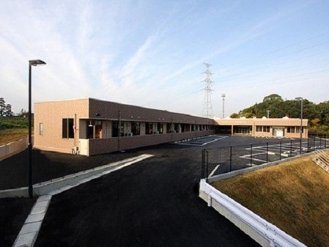 大きな駐車スペースが確保された、平屋建ての施設の外観