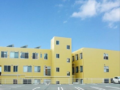 広々とした敷地に建っている、クリーム色の外壁で明るい印象の施設