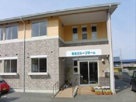 施設の外観である。２階建ての建物で、１階はレンガ調、２階は黄色の外壁である。右側に玄関があり、スロープと階段がある。