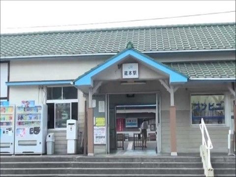 駅の屋根は瓦葺きになっている。左側に自動販売機が２機並んでいる。駅の前に階段があり、手すりが設置されている。