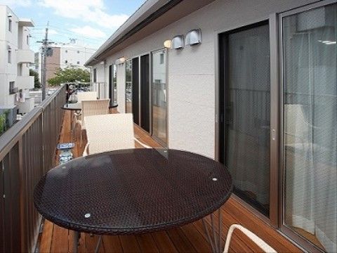 木製の板を床としているテラスには、円形のテーブルと椅子が複数用意されている。テラスの端は、転落防止用の柵で囲われている。