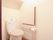 手すりが設置され、アイボリー色のトイレマットとカバーがついたトイレ