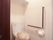 片手用の手すりが設置され、トイレカバーとマットが敷かれたトイレ