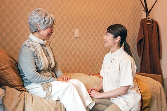 飲み物を飲みながらスタッフとの会話を楽しんでいる入居者様