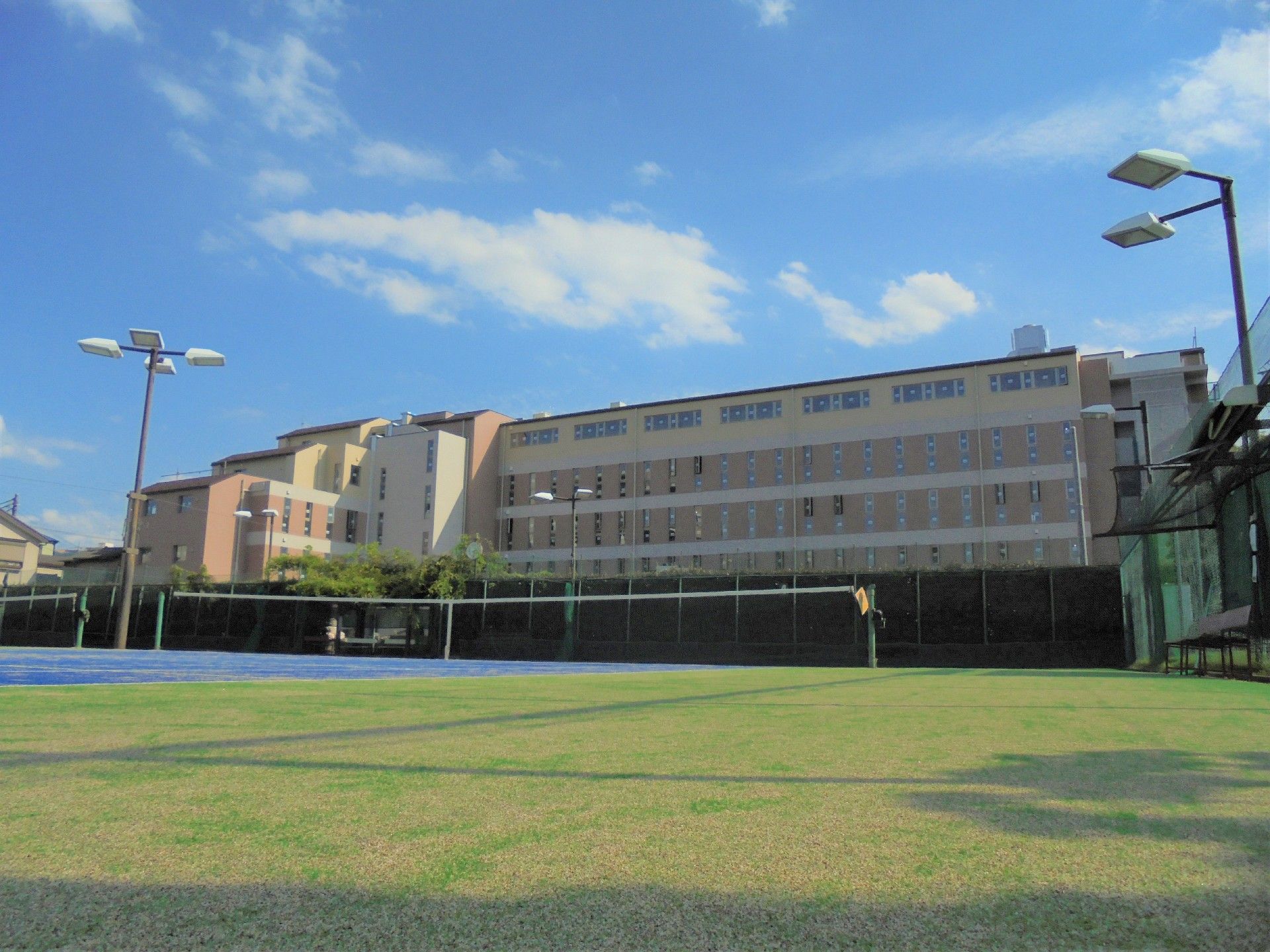 前に芝生の広場がある大きな建物の外観
