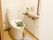 広々としたトイレには、赤紫色のマットと便座カバーが取りつけられている。便座には、金色のリボンが結ばれている。