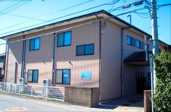 暖色系の外壁で、あたたかみある雰囲気の外観である。施設のまわりにフェンスが設けられており、安全性を確保している。