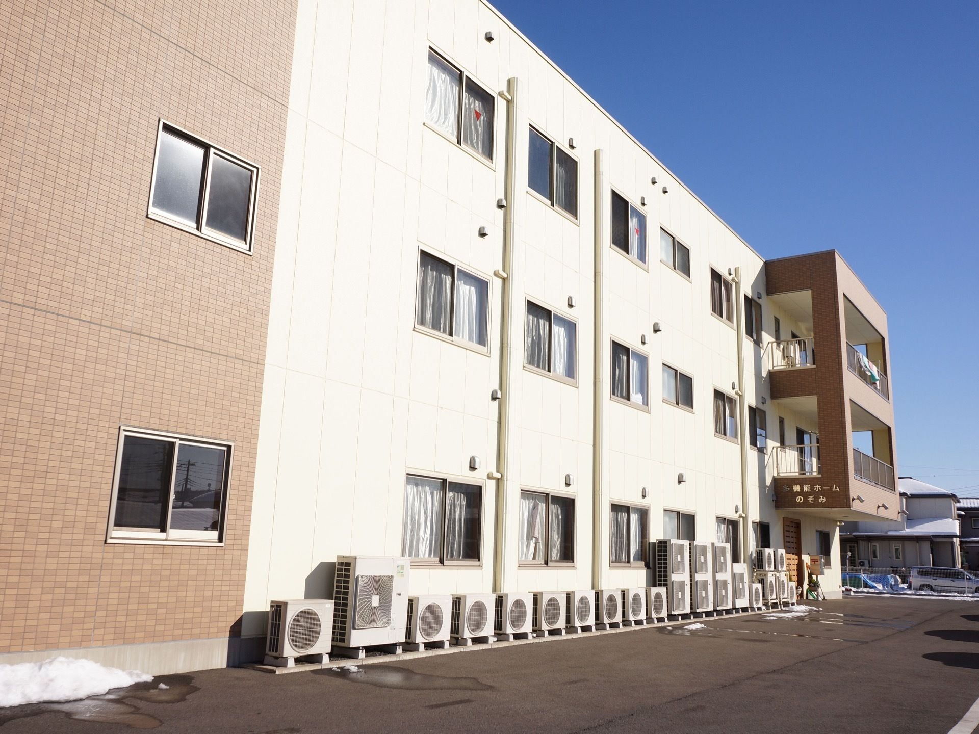 施設の建物は三階建てで、外壁は白とライトブラウンの配色である。前面には広い駐車スペースを設けている。