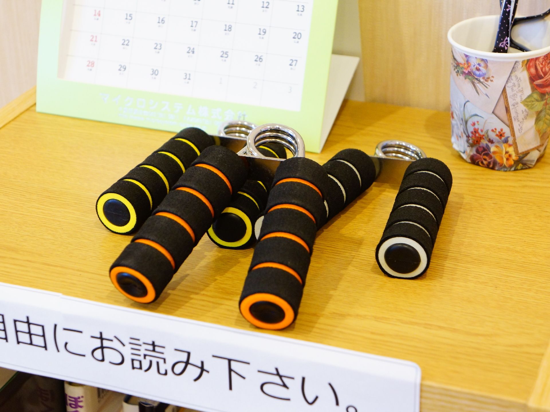 本棚の上には卓上カレンダーや、気軽に腕や手の運動ができる運動器具、メガネ等が置かれていて、自由にご利用いただける。