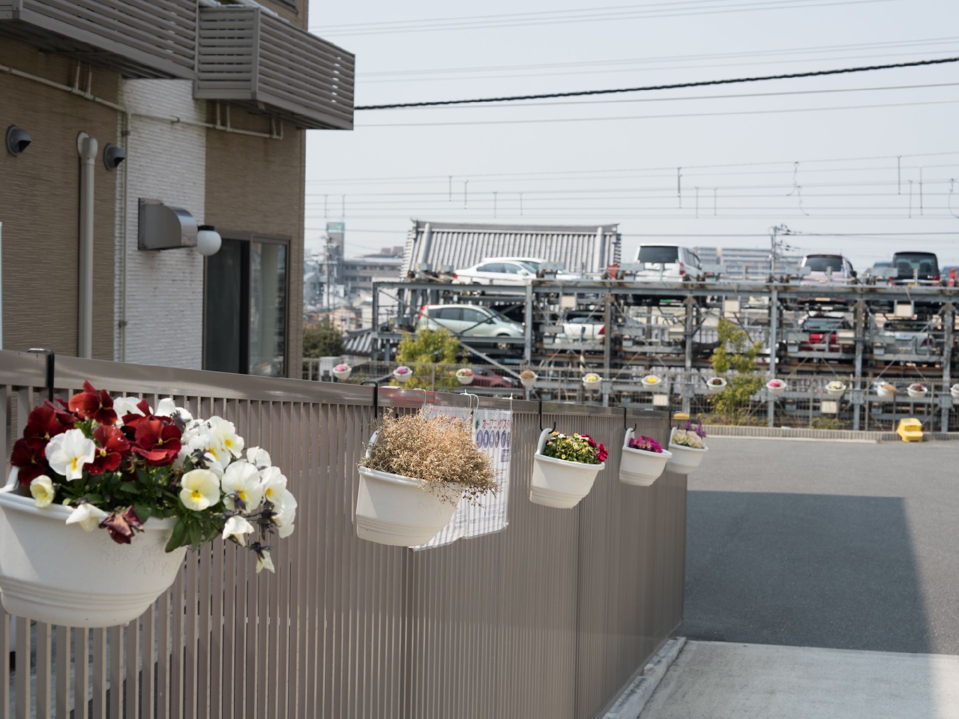 エントランスへ向かう駐車場部分には壁にかけられた花瓶やプランターがある。