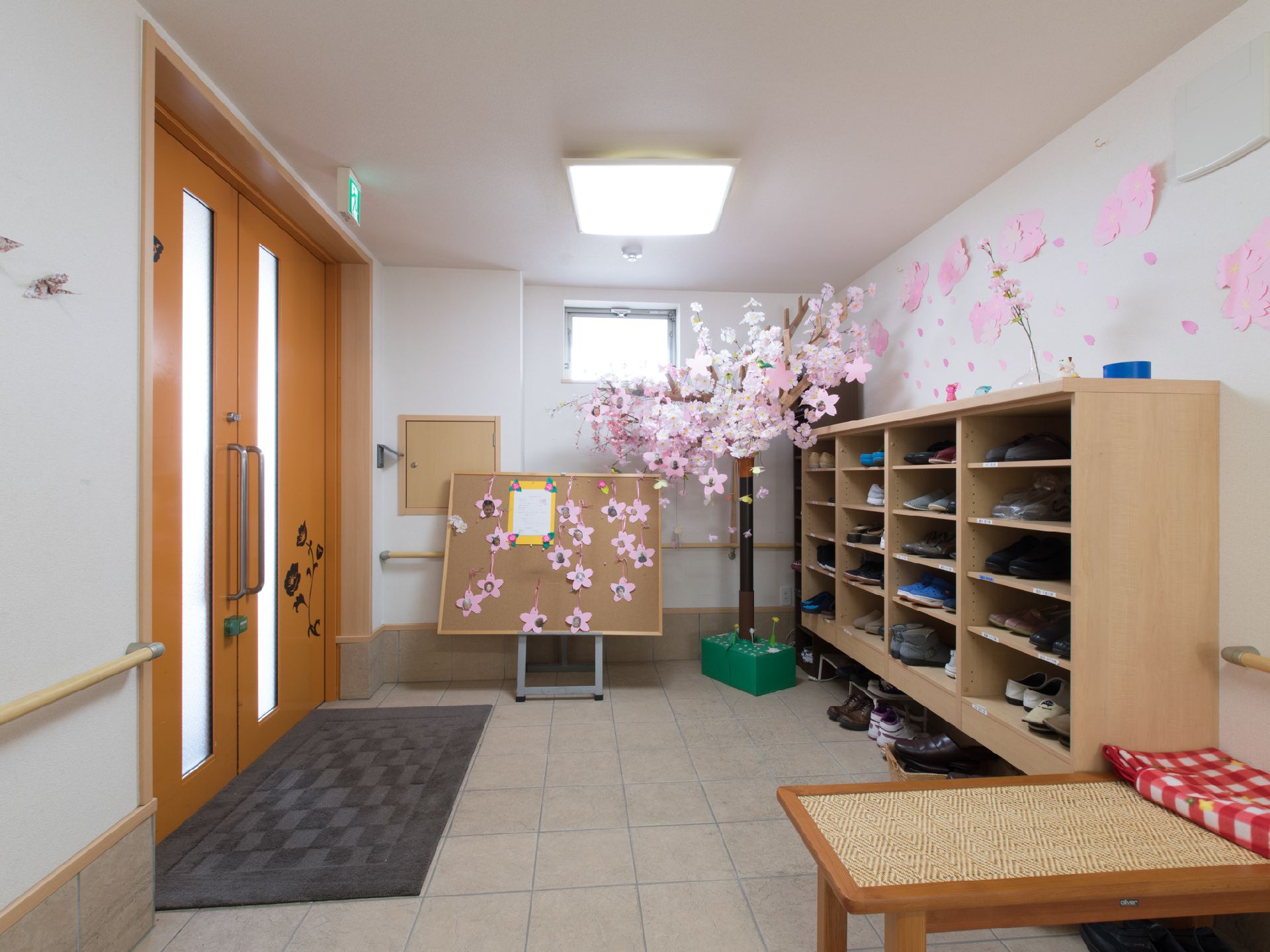 エントランス。入居者専用の靴箱がある。桜の装飾が壁一面に張られている。