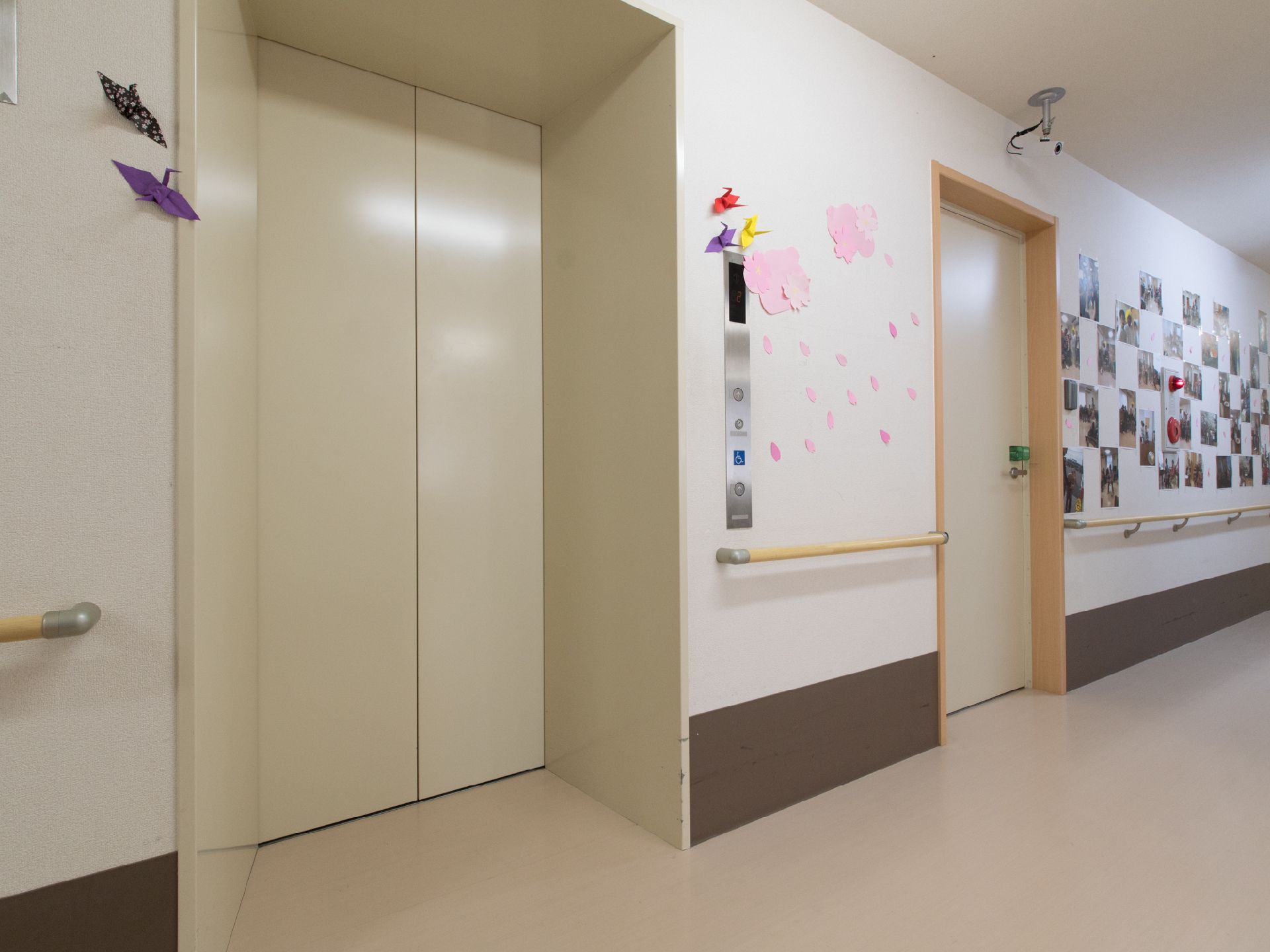 エレベーターが利用できるため、どんな方でも気軽に館内を行き来できるようになっている。また、近くの壁には折り紙などが貼られている。