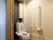 居室にある個人用トイレは、洗浄機能付き便器を採用。白い壁には同色の手すりがＬ字型に設置され、非常用コールボタンも備え付けられている。