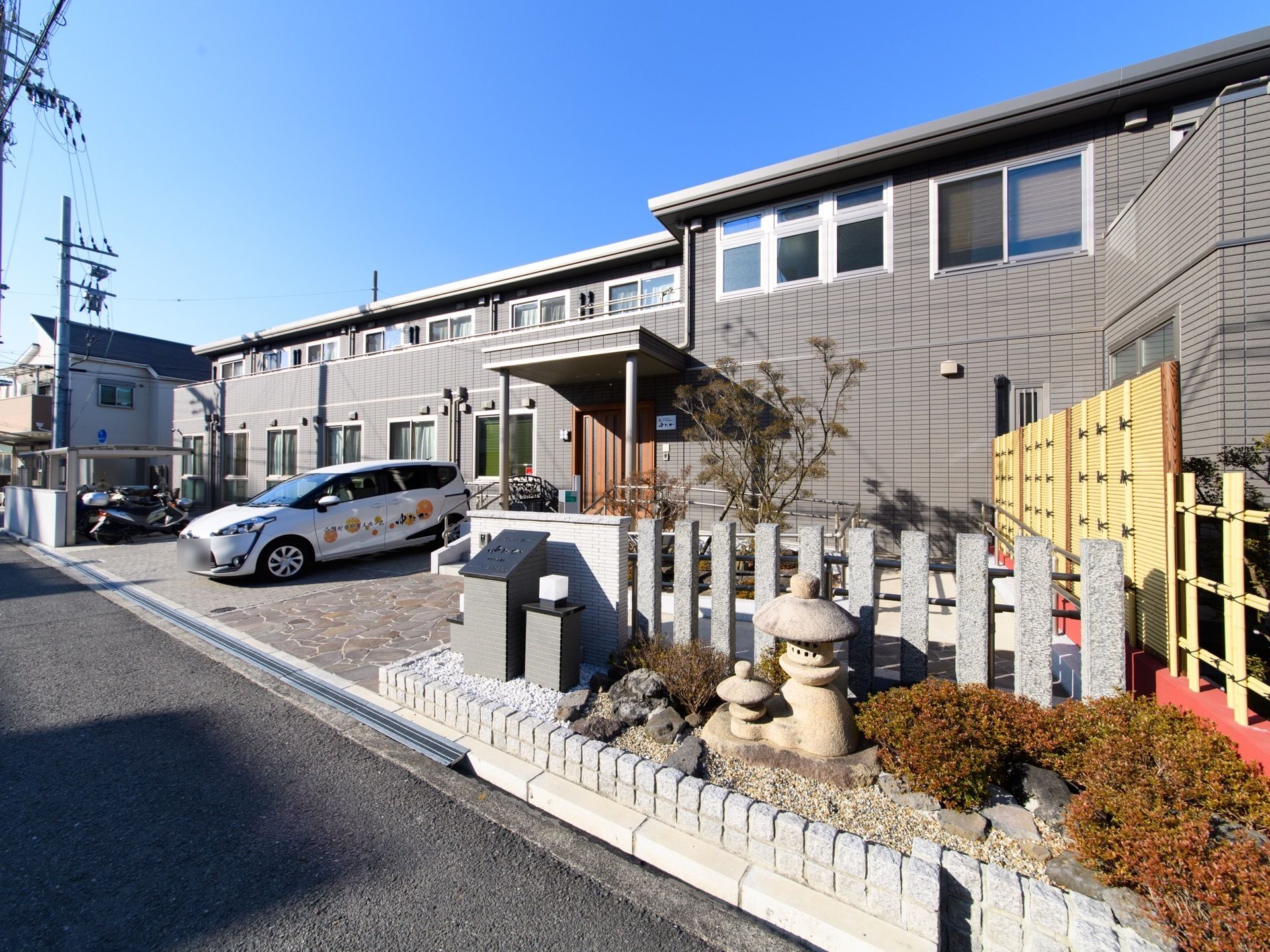 施設の建物は、２階建てで中央に屋根付きの玄関がある。建物の前には駐輪場と駐車場があり、車の来訪が可能になっている。