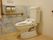 緊急時呼び出しブザーが備えられたトイレには、手すりが付けられている。壁はホワイト系のストライプで、一部が花柄である。