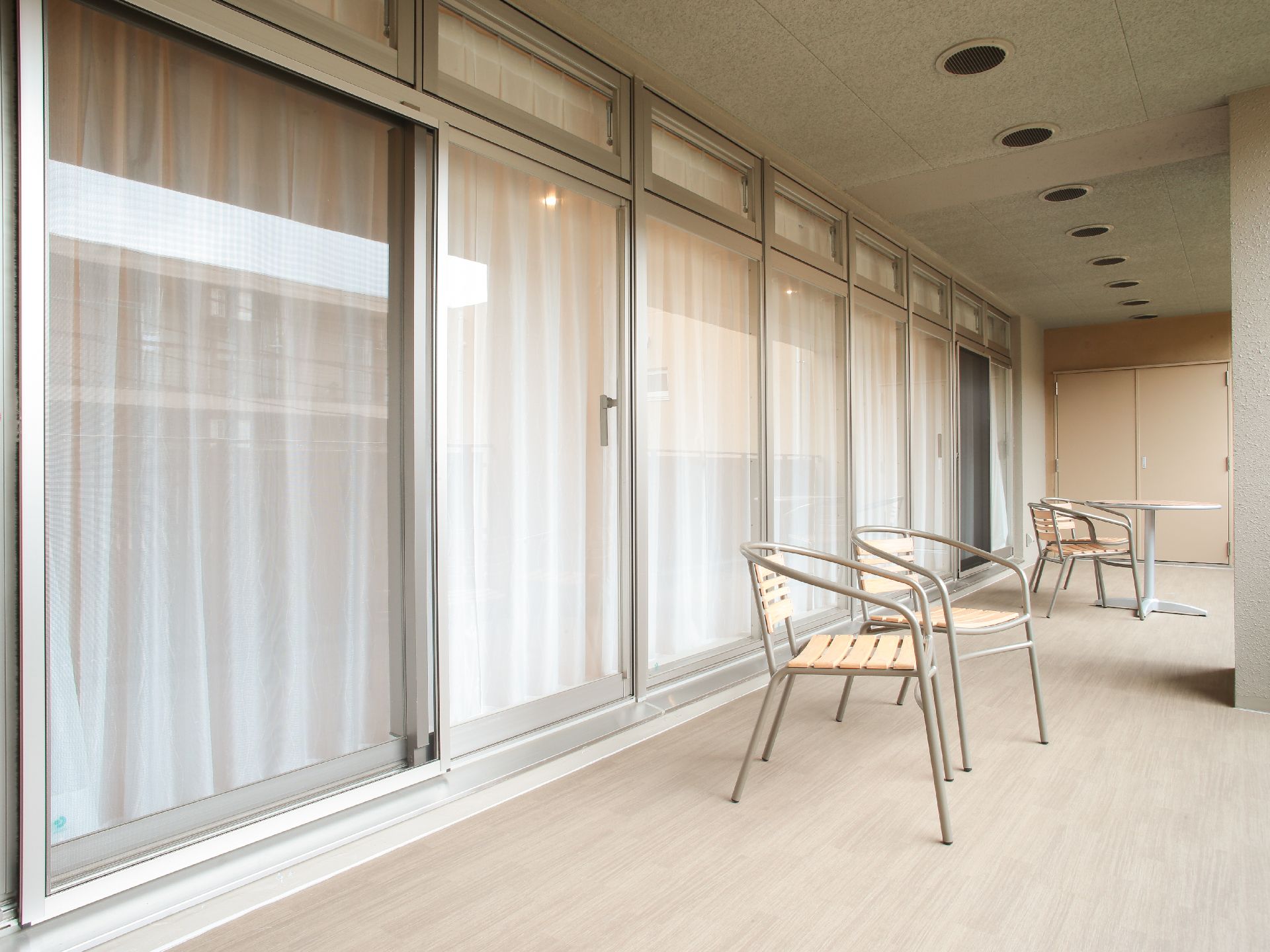 いくつかのテーブルやイスが置かれ複数の座席が用意されているデッキ部分。入居者に用意された共用スペースの一つ。