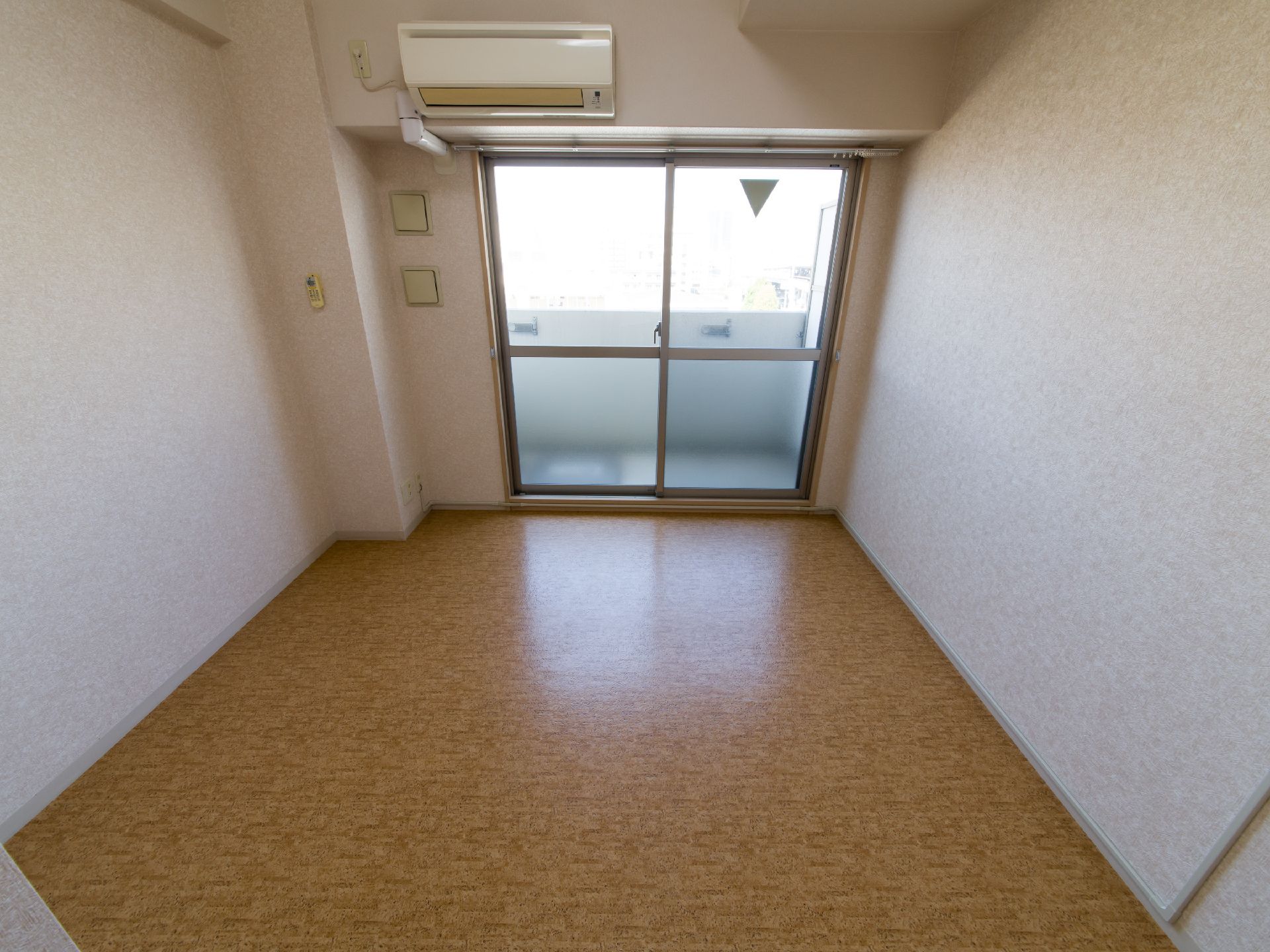 エアコンが設置されている。ベランダがある。白い壁でとても清潔感があるお部屋となっている。快適に暮らせる空間である。