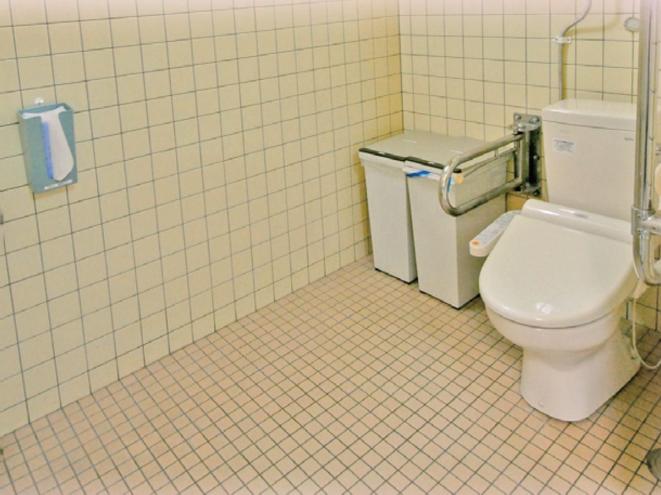 手すりがしっかりと付いているトイレである。全面タイル張りで清潔感がある。ごみ箱も設置されており、衛生面も徹底している。