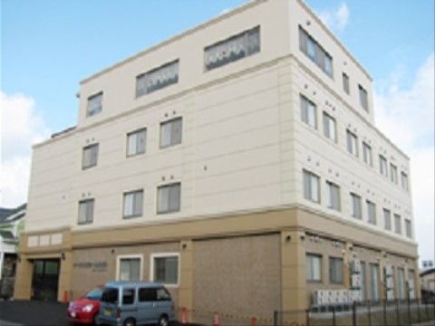 施設はツートンカラーの4階建てでシンプルな形になっている。玄関前には車も数台停められるスペースがある。