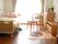陽光が差し込む明るい部屋に、２つのピンク色の枕が乗せられたベッドが設置されている。チェストの上に花瓶に生けられた花が飾られている。