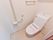 白色の壁にベージュ色の床のトイレスペースである。壁際には手すりを設置し、タオル掛けを備えている。緊急時のナースコールを取り付けている。
