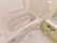 白色でまとめられた内装に黄緑色の１面の壁がある。浴槽横の壁にはエル型の手すりを取り付けている。傍には洗い場を設けている。