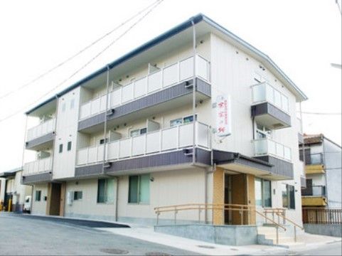 施設名の入った白い看板が掲げられた、3階建ての施設の外観