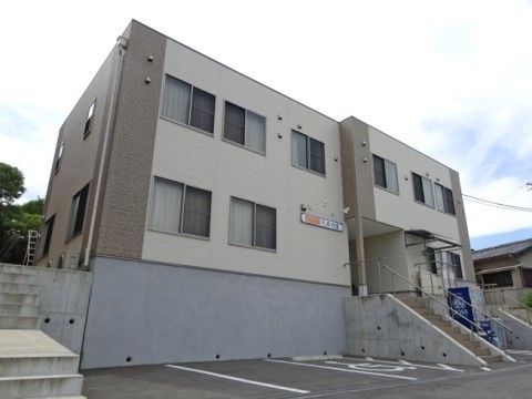 建物は白と茶色のツートンカラーで、シンプルな２階建てである。駐車スペースもとってあり、車の乗り入れも楽に行える。