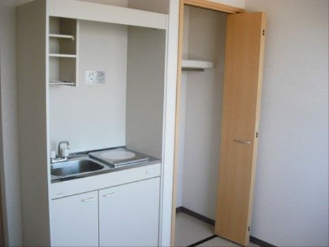 部屋にはキッチンやクローゼットが完備されている。キッチンには小さい流しとIHタイプのコンロがあり、下の部分は収納ができる。