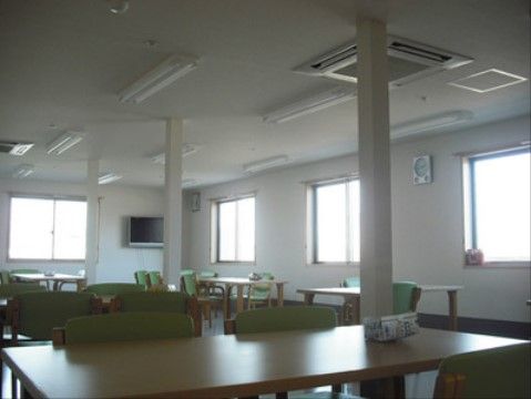 テーブルと椅子がたくさん設置されているので、大勢で利用できる。窓が四か所あり、明るい光が入る。壁にはテレビや時計が掛けられている。