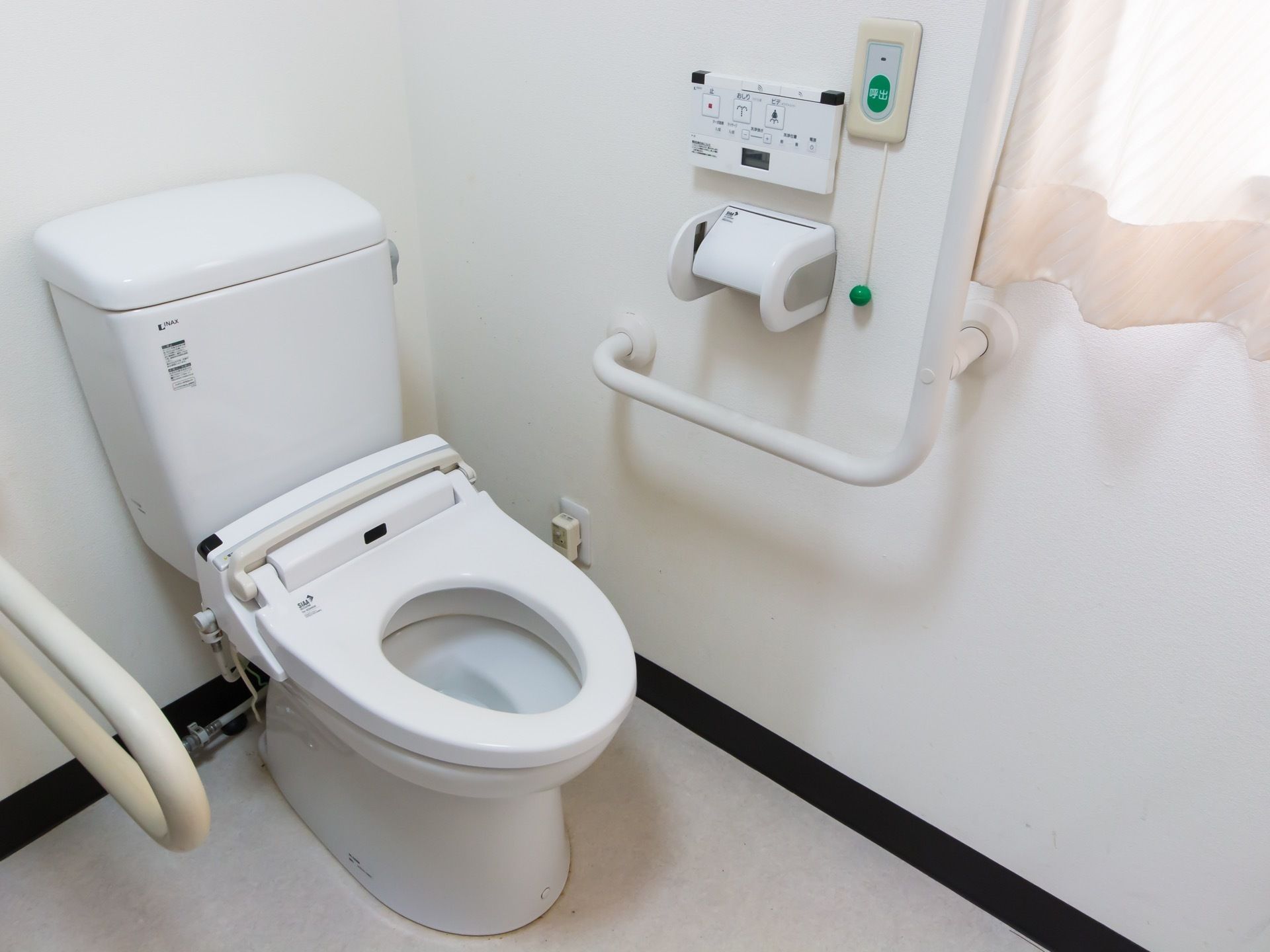 真っ白できれいなトイレが設置されている。温水洗浄便座になっており、壁に操作ボタンが取り付けられている。
